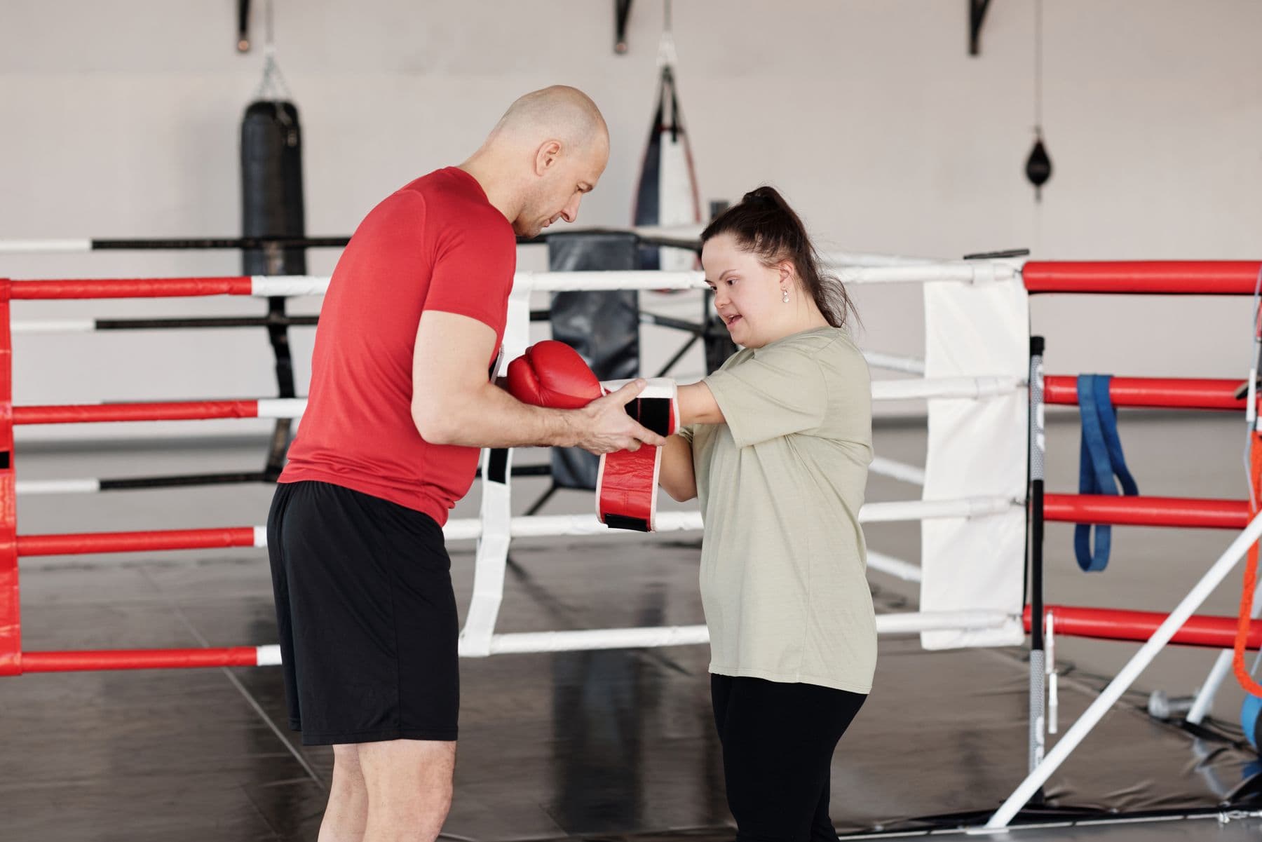 A coach helping a young woman with Down syndrome during an adaptive boxing session