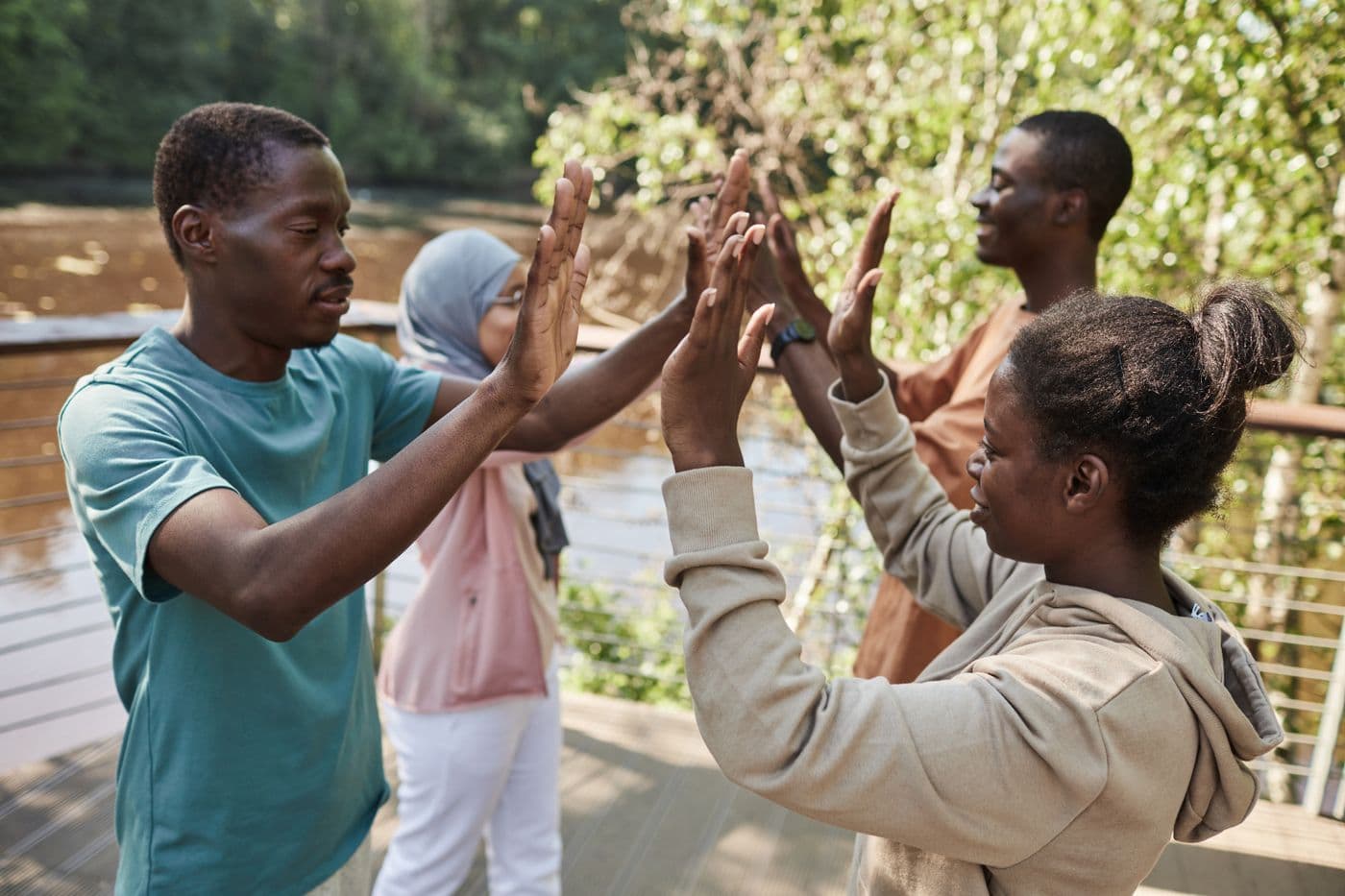 A happy group of young adults sharing high fives during an outdoor community activity