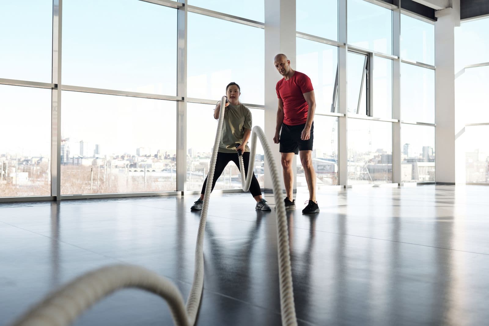 A coach supporting a young woman with Down syndrome during a fitness activity